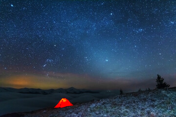 Space starry nights with a bright Milky Way on the backdrop of tourists with tents.