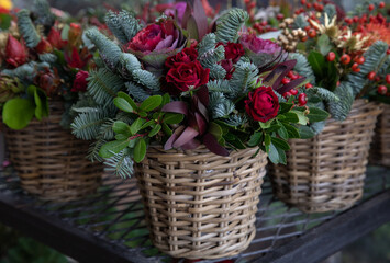 Beautiful flower arrangement of red roses, Brassica oleracea, natural spruce branches for winter festive indoor decor.