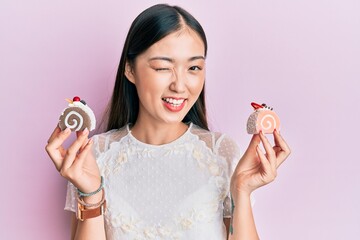 Young chinese woman holding cake sweets winking looking at the camera with sexy expression,...