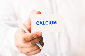 Word calcium on a white background with a syringe in hand. Medicine concept