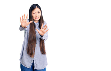 Obraz na płótnie Canvas Young beautiful chinese woman wearing casual shirt afraid and terrified with fear expression stop gesture with hands, shouting in shock. panic concept.