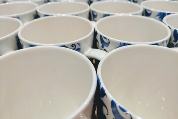 Colorful mugs on shelf in retailer gift shop.