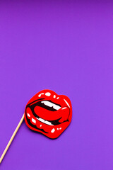 the image of beautiful bright red female lips in the form of a kiss on a solid purple background