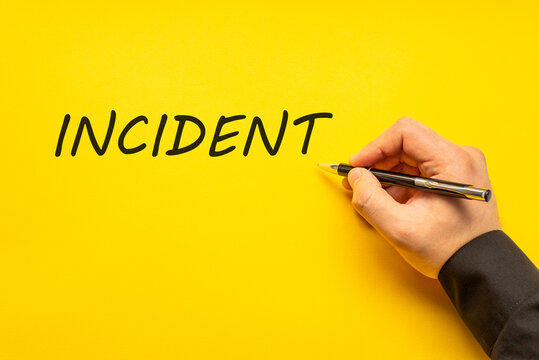 Male hand writes in black pen the word incident on a yellow background with copy space. Business concept photo