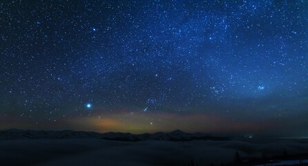 Naklejka premium Space starry nights with a bright Milky Way on the backdrop of tourists with tents.