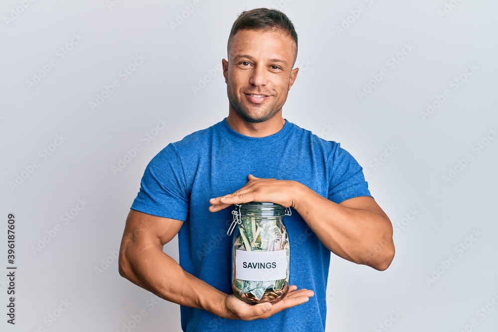 Sticker handsome muscle man holding jar with savings smiling with a happy and cool smile on face. showing te