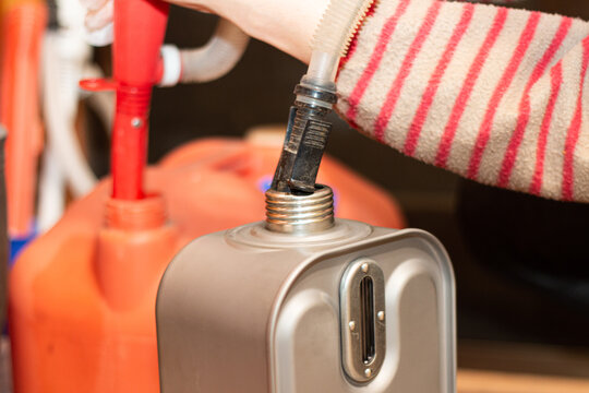 地震/台風/災害時の停電対策にもなる暖房器具「石油ストーブ/石油ファンヒーター」のタンンクに灯油を電動式ポンプで補給する女性の手元。電源不要 防災対策