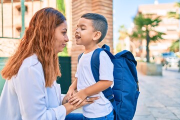 Adorable latin student boy and mom walking at the city.