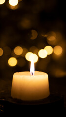 A candle burns against a blurred golden bokeh background. Close-up, blurred background. Festive New Year background.