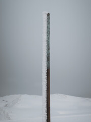 snow on a wooden pole with cyan color and snowy mountains in background