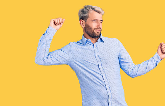 Young Handsome Blond Man Wearing Elegant Shirt Dancing Happy And Cheerful, Smiling Moving Casual And Confident Listening To Music