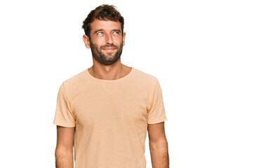 Obraz premium Handsome young man with beard wearing casual tshirt smiling looking to the side and staring away thinking.