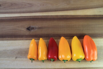 A few different colored peppers on a kitchen board