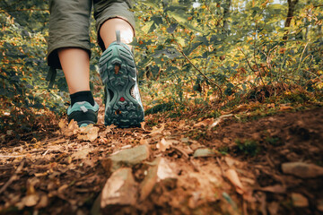 Hiker boots footsteps on muddy ground. Sole of shoe in motion on track. Walking hike. Close-up of woman traveler feet