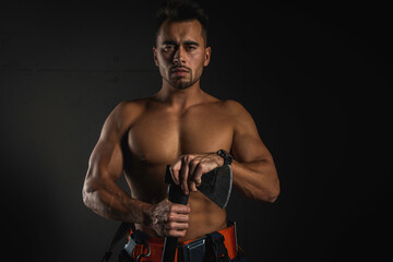 Fototapeta na wymiar young handsome adult, muscular firefighter in uniform holding an ax of fire equipment in his hands in front of him, pensively, isolated on a dark background. Low key. Protection concept