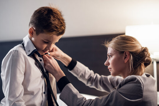 A close up picture of a mother fixing her little son's tie in the bedroom.