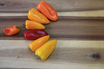 A few different colored peppers on a kitchen board