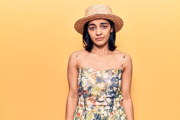 Young beautiful latin woman wearing summer hat skeptic and nervous, frowning upset because of...
