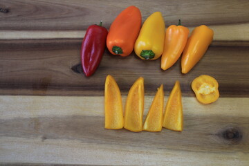 A few different colored peppers on a kitchen board