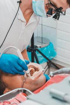 Dental clinic, private practice, the dentist uses binoculars for the best result and work, the process of removing tartar.