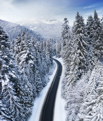 Aerial view on the road and forest in winter time. Natural winter landscape from air. Forest under...