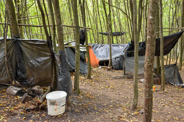 Migrants live in a wild camp. Refugees from Africa and Asia sleep in tents in the forest.