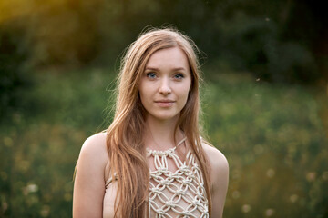 Beautiful young blonde woman with natural makeup in a field with flowers. The concept of natural cosmetics and harmony with nature.