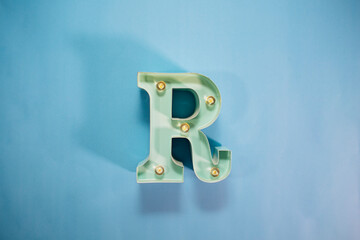 Turquoise letter R with lights, light blue background