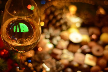 Illumination reflected in a glass of champagne on a blurred background of sweets