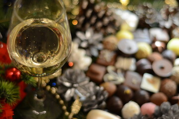 Fototapeta na wymiar Evening cristmass composition from a glass of champagne on a blurred background of assorted chocolates