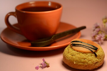 Cup of coffee with chocolate false and cake eclair on pink background