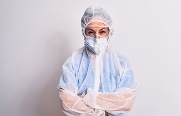 Middle age nurse woman wearing protection coronavirus equipment over white background skeptic and nervous, disapproving expression on face with crossed arms. Negative person.