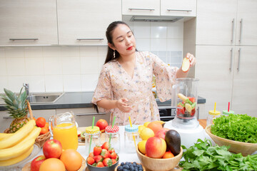 Happy woman enjoy preparing freshly squeezed fruits with vegetables for making smoothies for breakfast together in the kitchen.diet and Health concept.