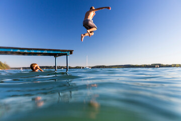 Junge springt vom Steg in den See
