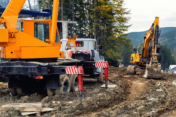 Heavy industrial machinery vehicles working in mud dirt bog road on top of mountain peak resort in...