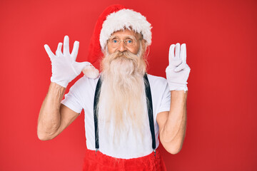 Fototapeta na wymiar Old senior man with grey hair and long beard wearing white t-shirt and santa claus costume showing and pointing up with fingers number eight while smiling confident and happy.