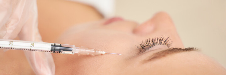 Near eye injection at spa salon. Doctor hands. Closeup. High quality. Pretty female patient. Beauty...