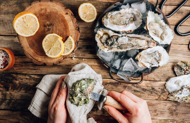 Fresh oysters with ice and lemon on a rustic wooden background.