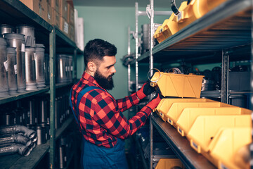 Handsome adult man working in car and truck spare parts warehouse.