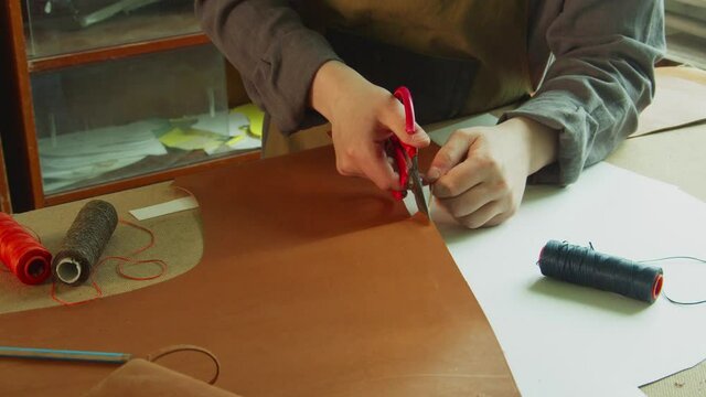 General view of the tanner's desktop, which is preparing to create designer shoes made of genuine leather. Cuts leather with scissors.