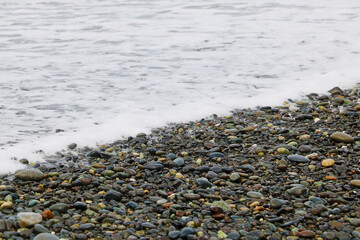 Pebble beach and foam from the sea on the background.