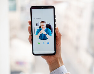 Woman holding smartphone with therapist contact