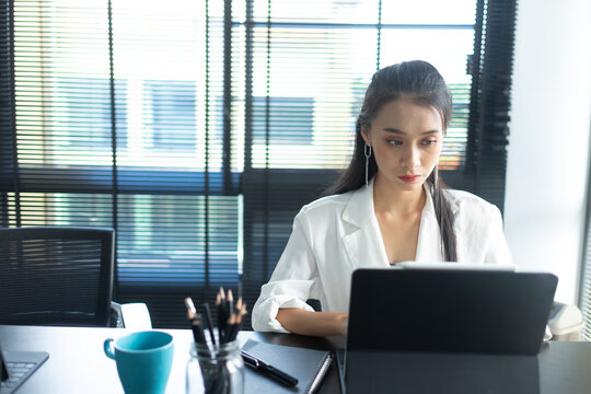 Portrait of a female office worker concentrating on her work with a digital tablet and stationery in the office room. 