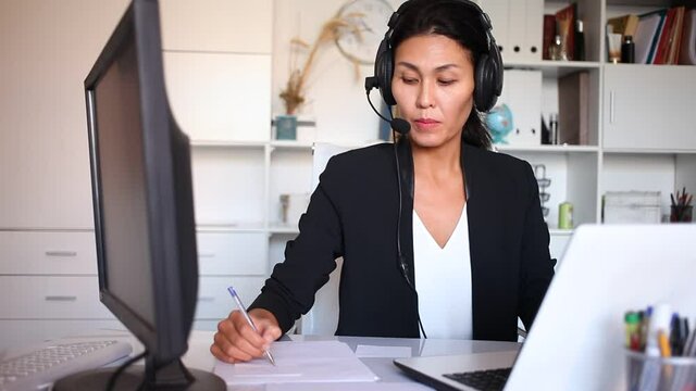 Portrait of woman call centre operator with headphones working in modern office . High quality FullHD footage