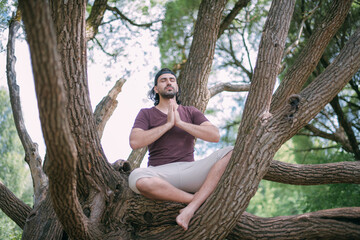 Young man meditates on a tree in the park