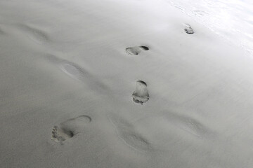 Footprints from the feet of a woman or man on the sand of the beach.
