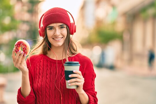 Young hispanic woman having breakfast using headphones at the city.