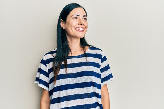 Beautiful young woman wearing casual clothes looking to side, relax profile pose with natural face and confident smile.