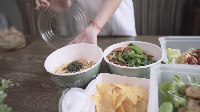 close up Young woman hands opening take away food container lid, food delivery setting up dining table, home convenience meal, new normal lifestyle ordering food, clean healthy eating organic salads