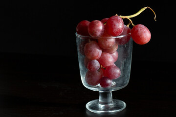 Red grapes, large bunch of fruits, fresh and tasty simple food on a dark background in a fancy minimal composition
